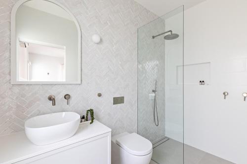 a bathroom with a toilet and a sink and a shower at Cape Beach House in Byron Bay