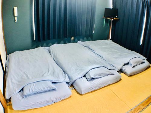 una pila de almohadas blancas sentadas en una cama en Habitacion NIIYA Mt Fuji en Fujikawaguchiko