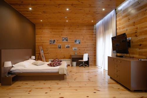 Schlafzimmer mit Holzwänden, einem Bett und einem TV in der Unterkunft Patio di Fiori in Luzk