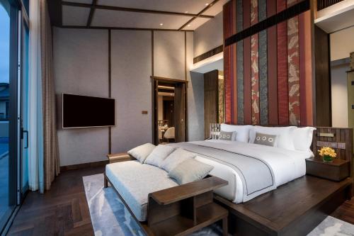 a bedroom with a large bed and a tv at Angsana Zhuhai Phoenix Bay in Zhuhai