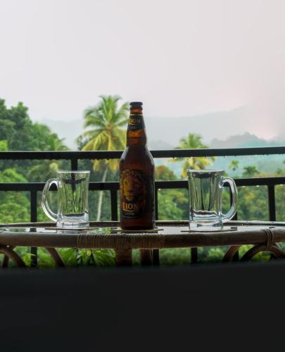 a bottle of beer and two glasses on a table at Chathu Holiday Home in Kandy