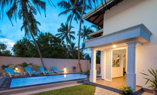 a villa with a swimming pool and palm trees at Villa Mer Vue in Ambalangoda