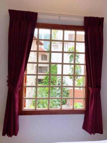 a window with red curtains in a room at Poolside Villa in Phnom Penh