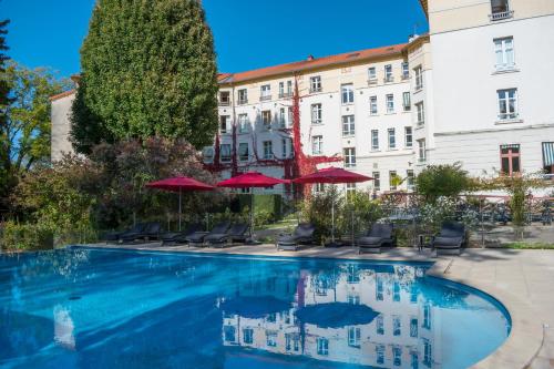 a pool with chairs and umbrellas in front of a building at Logis Les Loges du Parc in La Roche-Posay
