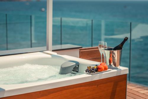 Nautilus Hotel في جيارديني ناكسوس: حوض استحمام مع زجاجة من النبيذ وكأس