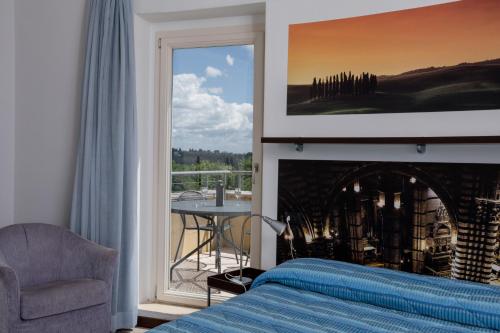 una camera con un letto e una sedia e una finestra di Porta Pispini Residence a Siena
