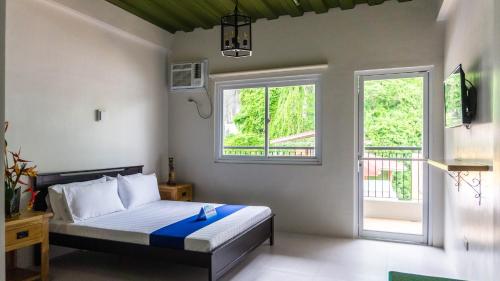 a bedroom with a bed and two windows at South Anchorage Inn in El Nido