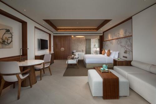 a hotel room with a bed and a couch and a table at Angsana Zhuhai Phoenix Bay in Zhuhai