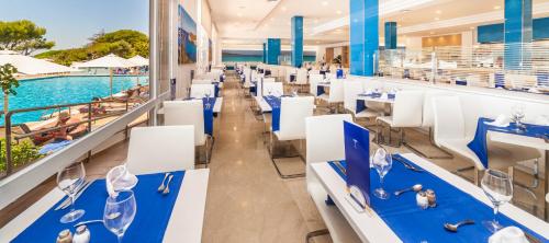 een restaurant met blauwe tafels en witte stoelen naast een zwembad bij Globales Lord Nelson in Santo Tomás