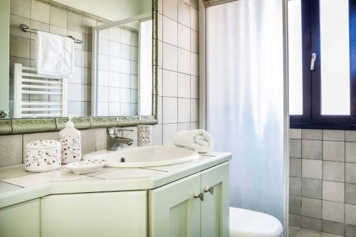a white bathroom with a sink and a mirror at Villa Nissaki in Kaligata