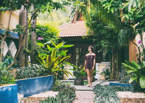 a woman walking through a garden in front of a building at Lost Paradise Resort in Batu Ferringhi