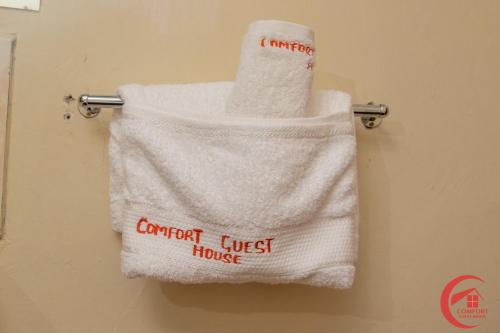 a towel with the words comfort just house hanging on a rack at Comfort Guest House in Kericho