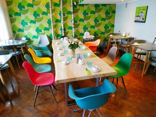 a dining room with a long table and colorful chairs at Rheinland Hotel in Bonn