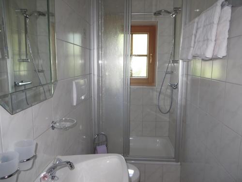 ein weißes Bad mit einer Dusche und einem Waschbecken in der Unterkunft Haus Moosbrunn in Alpbach