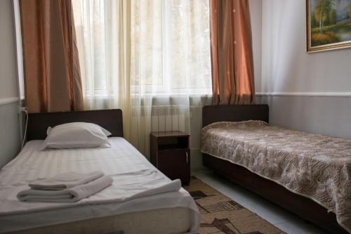 two beds in a small room with a window at Astana Hotel in Almaty