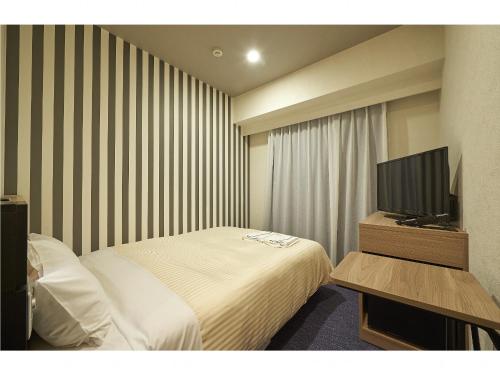 a hotel room with a bed and a flat screen tv at Sotetsu Fresa Inn Kamakura-Ofuna Higashiguchi in Kamakura