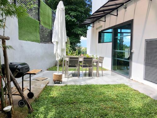 a patio with an umbrella and a table with a grill at Baan Saint-Tropez Seaview Villas Kata Beach in Kata Beach