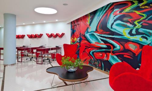 a room with red chairs and a painting on the wall at Iolida Beach by Smile Hotels in Agia Marina Nea Kydonias