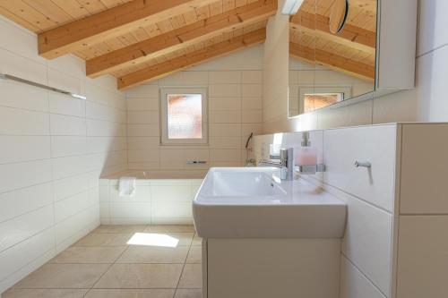 Chalet Gousweid- Jungfrau Apartment في وايلدرسويل: حمام أبيض مع حوض ومرآة