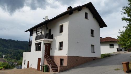 a white house with a staircase on the side of it at Ferienhaus KorsikaBlick in Unter Schönmattenwag