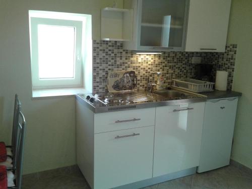 a white kitchen with a sink and a window at Studio-Apartman-Diana in Brseč