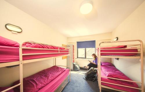 una mujer sentada en el suelo en una habitación con literas en Belfast International Youth Hostel en Belfast