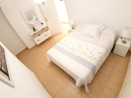 - une petite chambre blanche avec un lit et un miroir dans l'établissement Apartamento Grande-Centro Barrio Playa, à Alicante