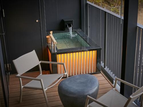 a balcony with a tub with a chair and a stool at Kumano-bettei Nakanoshima in Katsuura