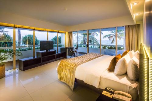 a bedroom with a large bed and large windows at Mount Lavinia Hotel in Mount Lavinia