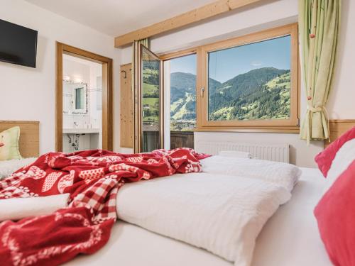 a bed with a red blanket on it in front of a window at Apartment Aschenwald Elisabeth in Ramsau im Zillertal