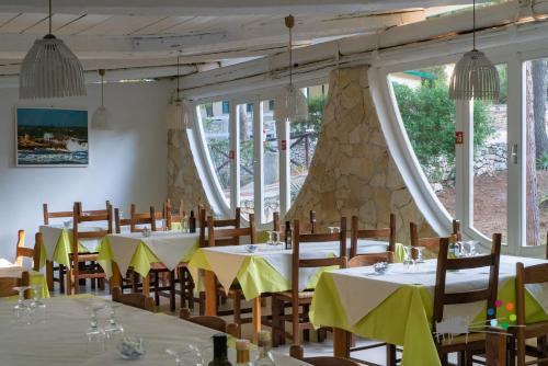 una sala da pranzo con tavoli, sedie e finestre di Villaggio Camping Punta Lunga a Vieste