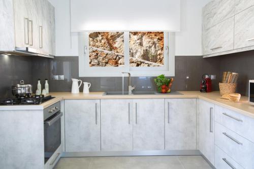a kitchen with white cabinets and a sink at Rachi Sea View White Villa in Episkopos