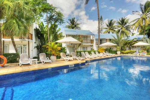 ein großer Pool mit Stühlen und Sonnenschirmen in der Unterkunft Cocotiers Hotel – Mauritius in Port Louis