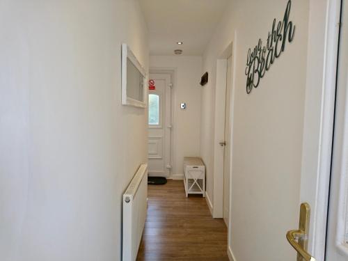 un corridoio con pareti bianche e pavimento in legno di Seaesta Apartments a Macduff