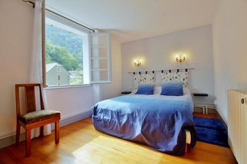 ein Schlafzimmer mit einem Bett mit blauer Decke und einem Fenster in der Unterkunft Gite du Hougarou in Ferrières