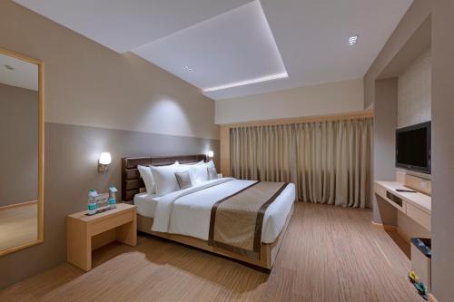 una camera con letto e TV a schermo piatto di The Fern Residency Aurangabad ad Aurangabad