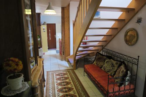 a hallway with a staircase with a couch and a rug at L'Union B&B - Chambres d'hôtes in Tramelan