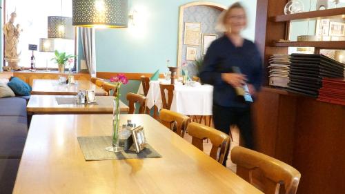 a woman walking in a restaurant with tables and chairs at Hotel Dalberg in Sankt Martin