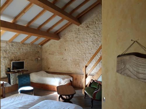 a bedroom with two beds and a tv in a room at La SERPAUDERIE in Saint-André-de-Lidon