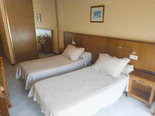 a hotel room with two beds and a table at Hotel Cristaleiro in Gondomar