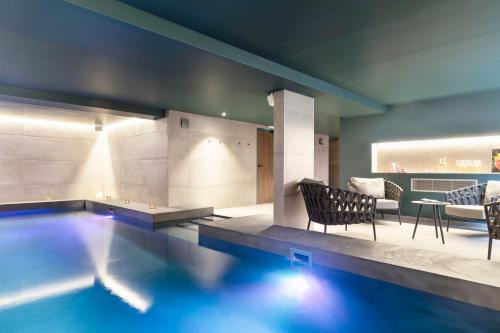 a swimming pool with chairs and a table in a room at Black Bass Hotel in Sévrier