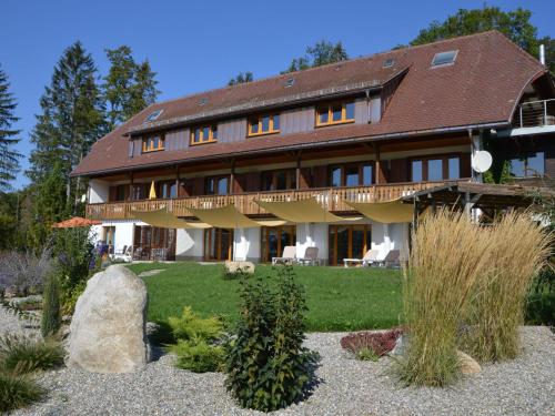 a large wooden house with a garden in front of it at Apartment in the Black Forest with balcony in Urberg