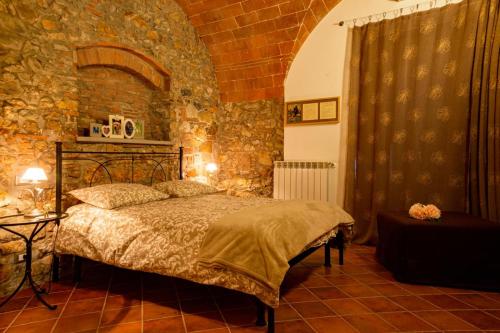 - une chambre avec un lit et un mur en pierre dans l'établissement Agriturismo Il Cuscino Nel Pagliaio, à Campiglia Marittima