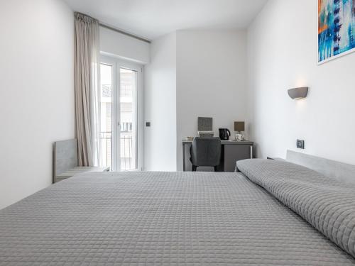 a white bedroom with a large bed and a desk at Diaz Apartment in Cagliari