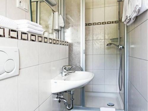 biała łazienka z umywalką i prysznicem w obiekcie Pension Braun w mieście Winterberg
