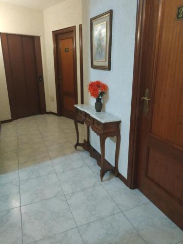 a hallway with a table with a vase of flowers on it at Hotel Cristaleiro in Gondomar