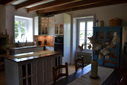 une cuisine avec une table avec un vase de fleurs dessus dans l'établissement Le Figuier, Large house with pool, gym & separate gite, à Saint-Ythaire