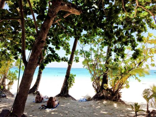 a group of people sitting on the beach under trees at Cocoloco Beach Resort in Boracay