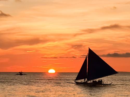 a sail boat in the ocean at sunset at Cocoloco Beach Resort in Boracay