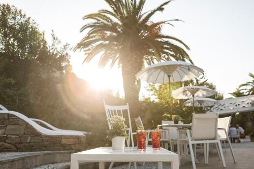 a group of tables and chairs with a palm tree at Mandraki Village Boutique Hotel in Koukounaries